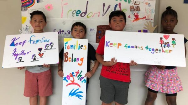 Three students from the Somerville Freedom School hold handmade signs: Keep Families Together