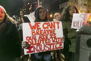 Black Lives Matter protestor holds a sign: We can't breathe. Our air is polluted with injustice.