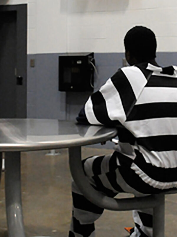 Incarcerated juvenile inmate sits at table