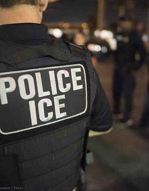 Back of officer with "Police ICE" vest