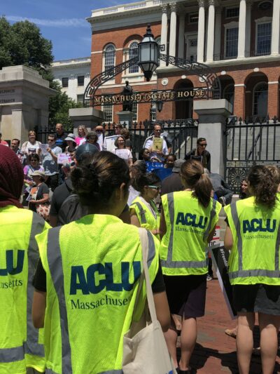 Volunteers wearing bright ACLU vests in front of the Massachusetts State House