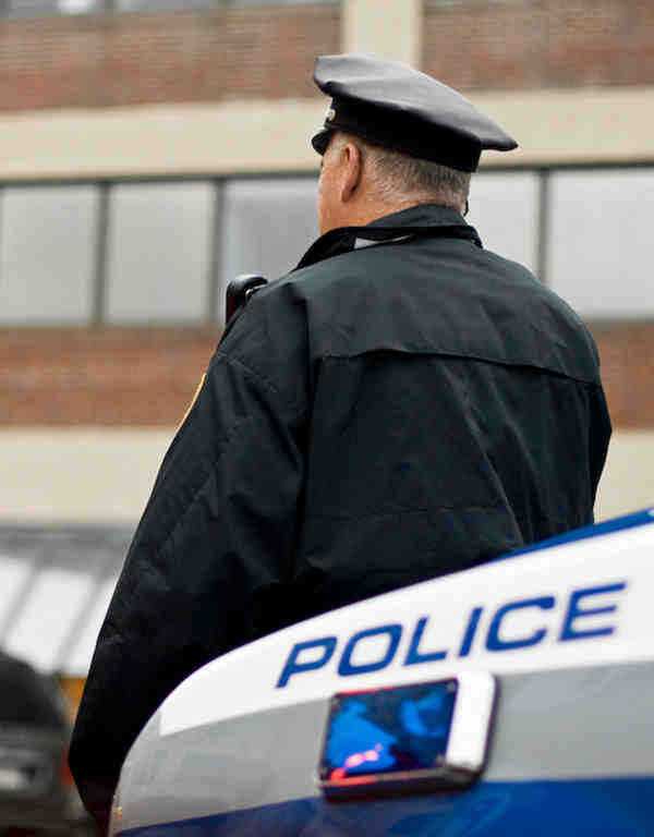 Police officer leaning against police car