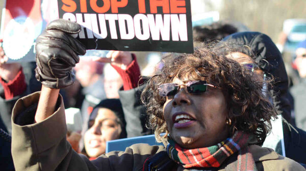 Protestor stands with "stop the shutdown" sign