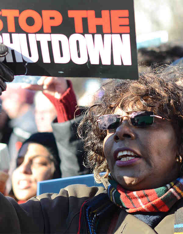 Protestor stands with "stop the shutdown" sign