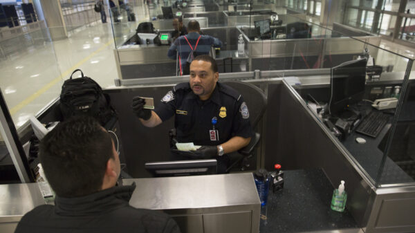 Customs and Border Patrol officer checks someone's passport at an airport