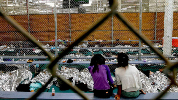 Two young girls watch a World Cup soccer match on a television from their holding area where hundreds of mostly Central American immigrant children are being processed and held