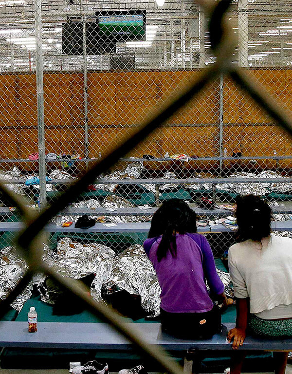 Two young girls watch a World Cup soccer match on a television from their holding area where hundreds of mostly Central American immigrant children are being processed and held