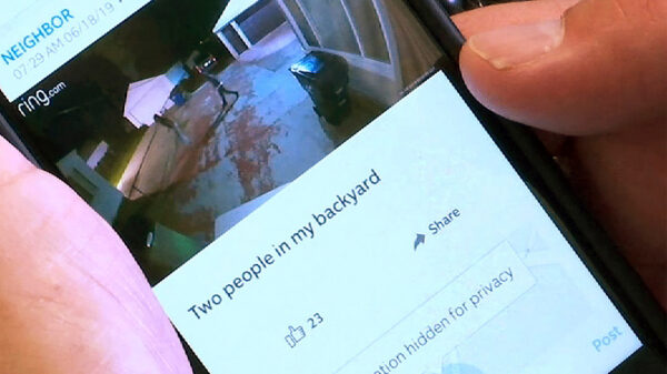 A person using the Ring smartphone app showing an image of two people in their backyard