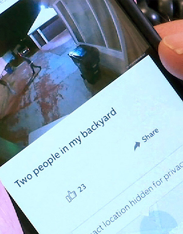 A person using the Ring smartphone app showing an image of two people in their backyard