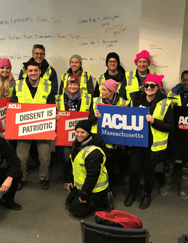 Volunteers in bright yellow ACLU vests hold ACLU signs