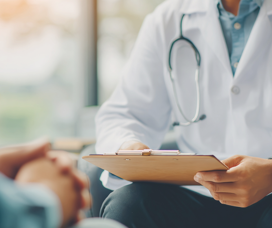 Photo of doctor's shoulder in a white coat. Their equipment is visible over their shoulder and a clip board is held in the foreground