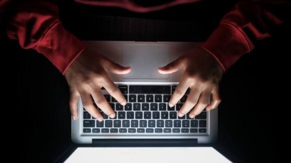 Laptop viewed from the top vertically and individually in a red sweatshirt is typing.