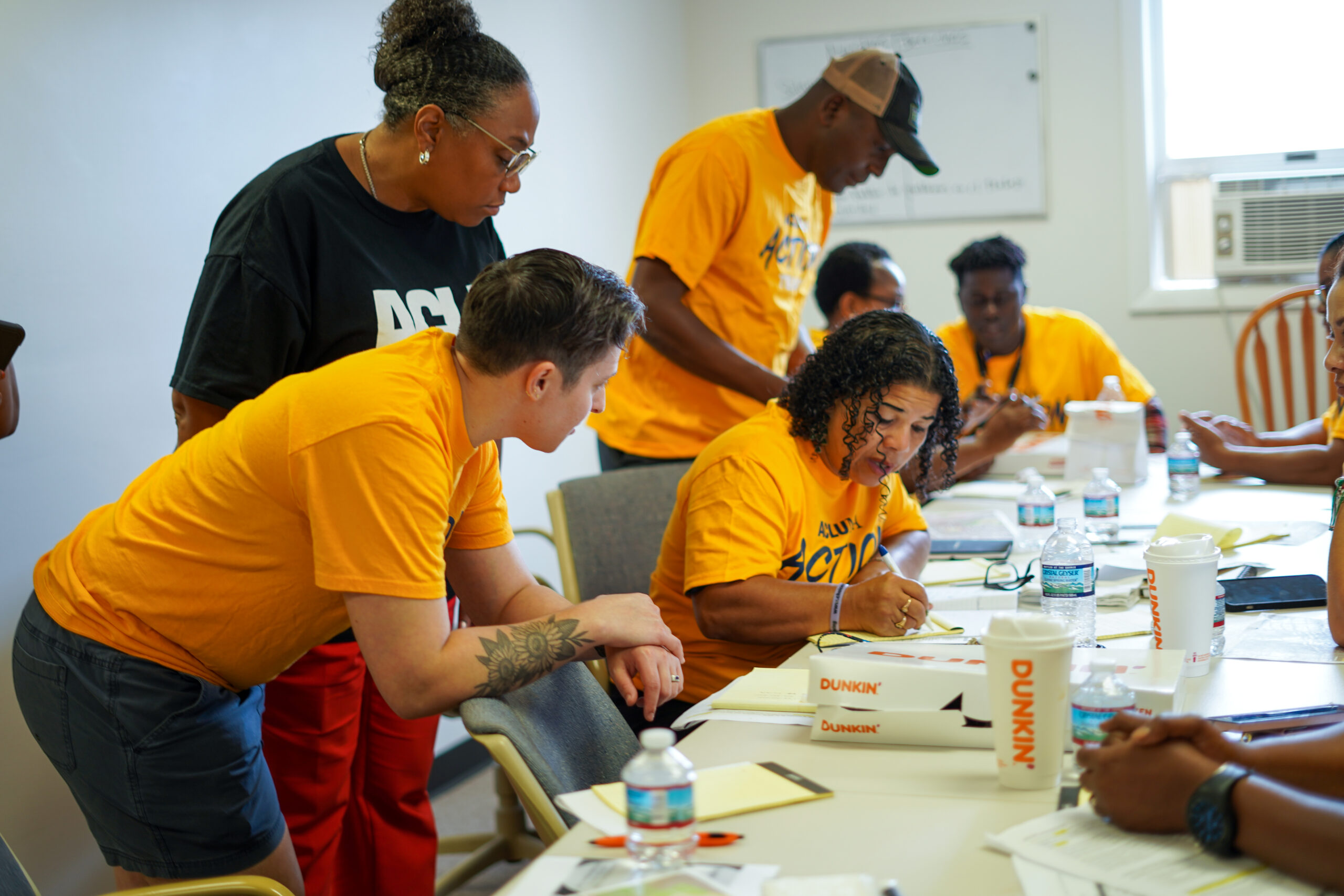 Individuals sit around a table preparing materials for BIPOC To The ballot Box