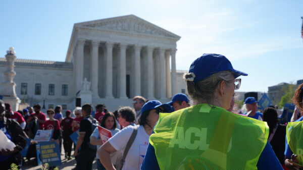 Supreme Court of the United States with rally happening outside. A crowd of people is stood outside the court.