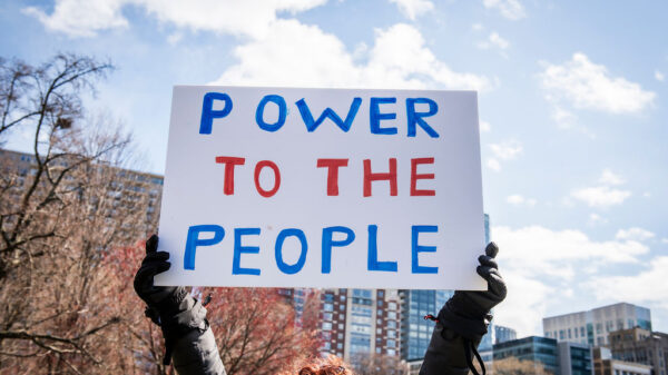 A protest sign is held in the air reading "Power to the People"