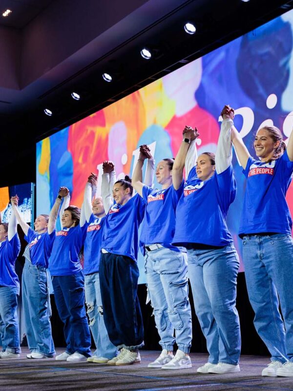 ACLU Members celebrate with raised connected hands on a stage at the Bill of Rights Gala in 2025