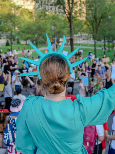 Person dressed at Lady Liberty facing the Boston Common from the Statehouse steps.