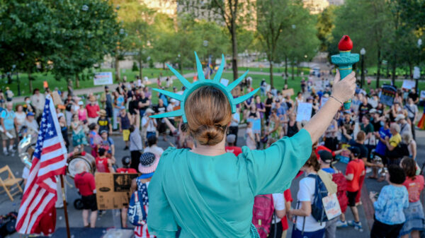 Person dressed at Lady Liberty facing the Boston Common from the Statehouse steps.
