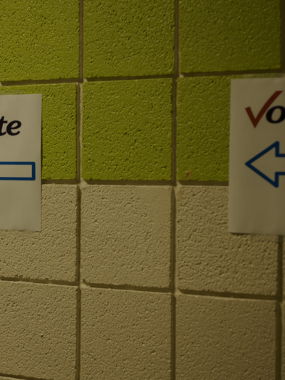 Concrete walls show paper signs that read "vote: