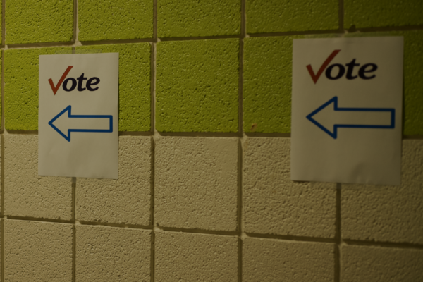 Concrete walls show paper signs that read "vote: