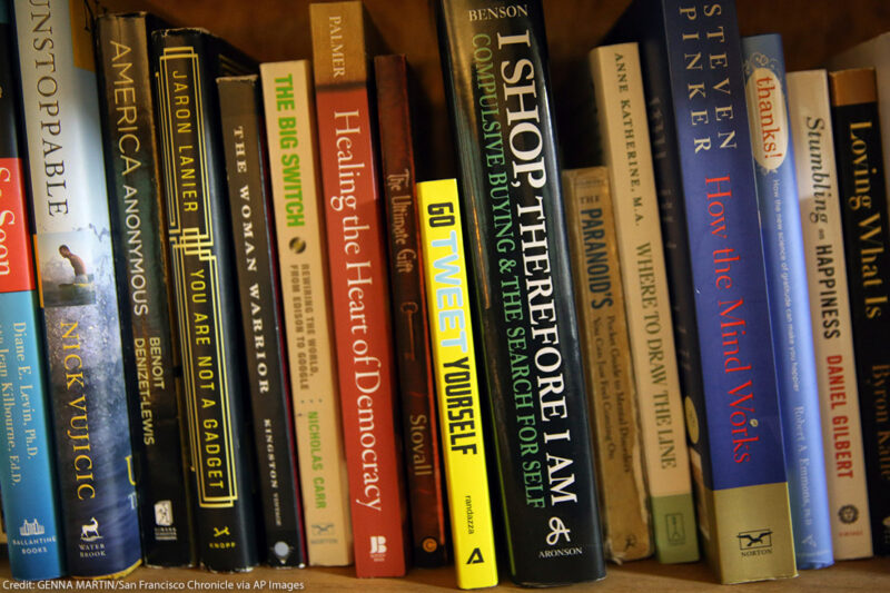 A set of book on a shelf leaning to the left. The image is zoomed in to show just the spines of the books. 
