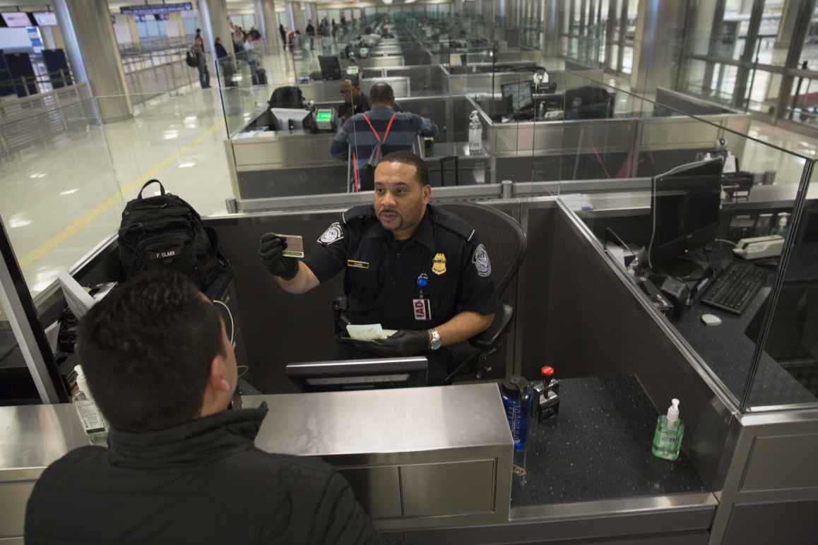 Customs and Border Patrol officer checks someone's passport at an airport