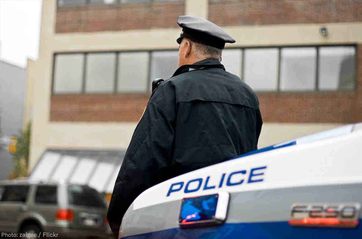 Police officer leaning against police car