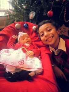 young boy and his baby sister pose near a Christmas tree