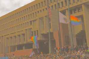 LGBTQ flags and banners decorate Boston City Hall Plaza as a large crowd attends a vigil 